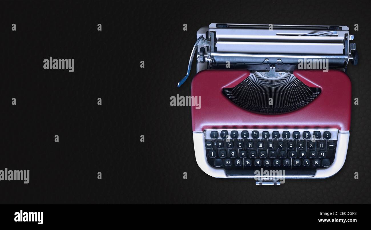 Macchina da scrivere meccanica a destra su uno sfondo orizzontale grigio scuro. Macchina di tipo metallico rosso con spazio di copia per il testo. Concetto di notizie. Foto Stock