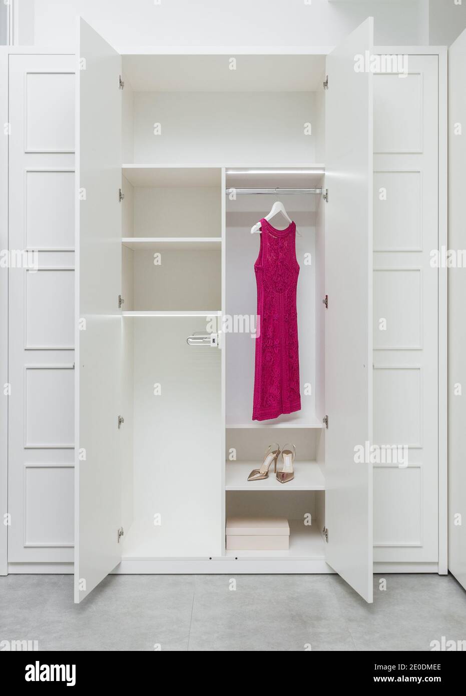 Abito rosa e scarpe in un guardaroba bianco vuoto come parte di un interno moderno. Arredamento interno moderno Foto Stock