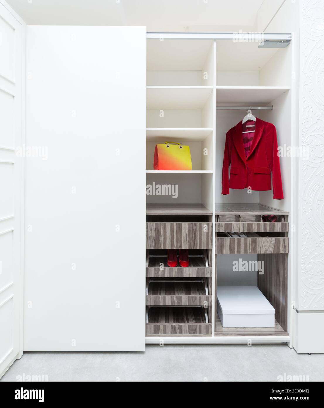 Blazer rosso donna e una borsa in un armadio bianco. Concetto di produzione di mobili Foto Stock