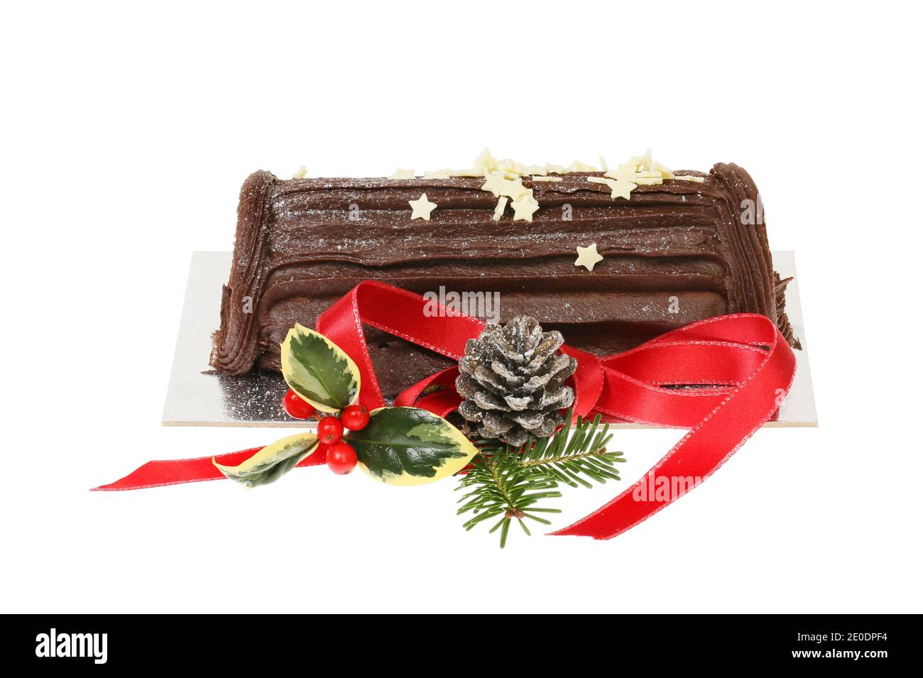 Cioccolato Natale Yule log decorato con stelle di cioccolato bianco e un nastro rosso con foglie di stagione, isolato contro il bianco Foto Stock