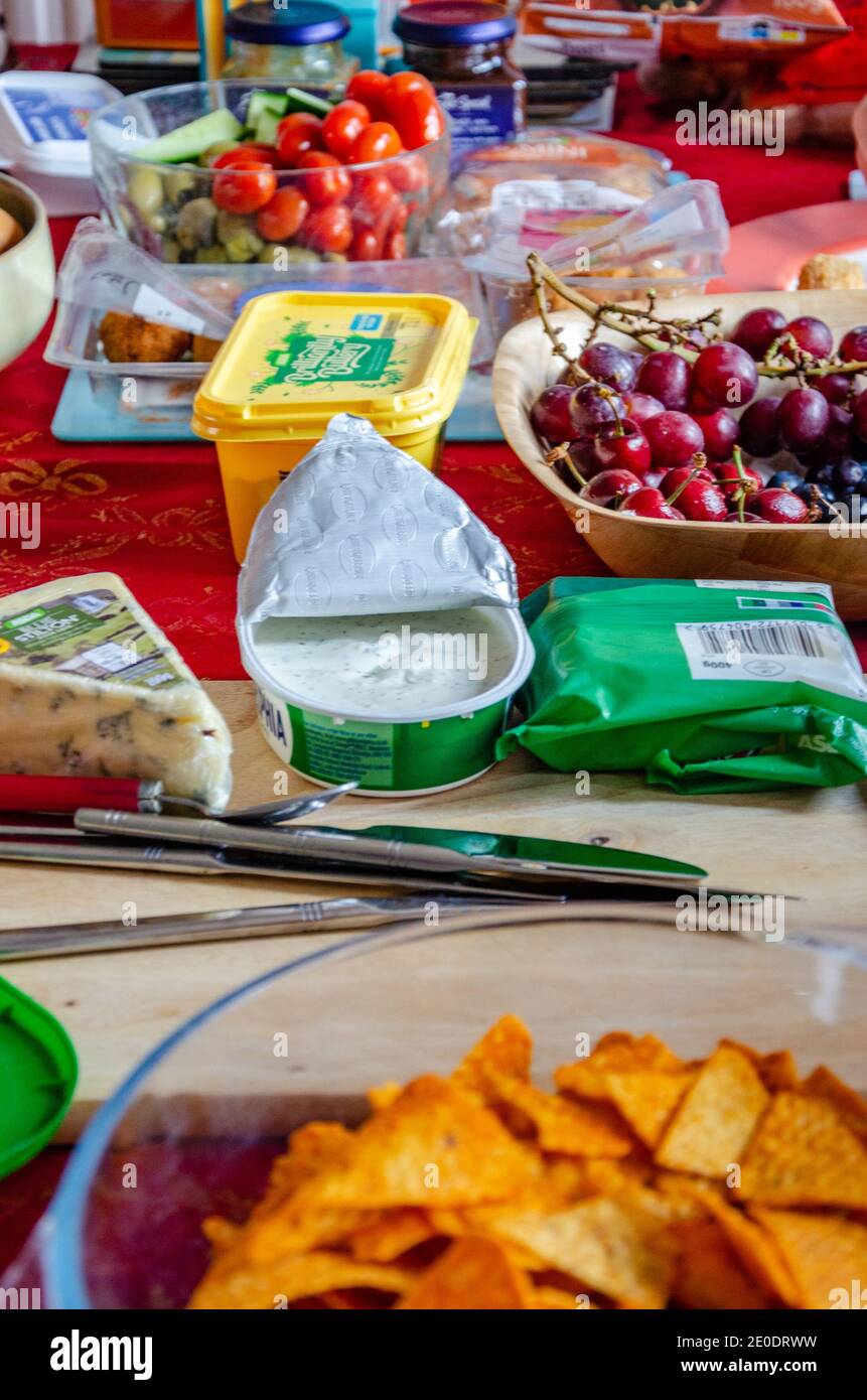 Una selezione di cibi tra cui formaggi, frutta e verdure da insalata, preparati su un tavolo per un pranzo a buffet a casa. Foto Stock