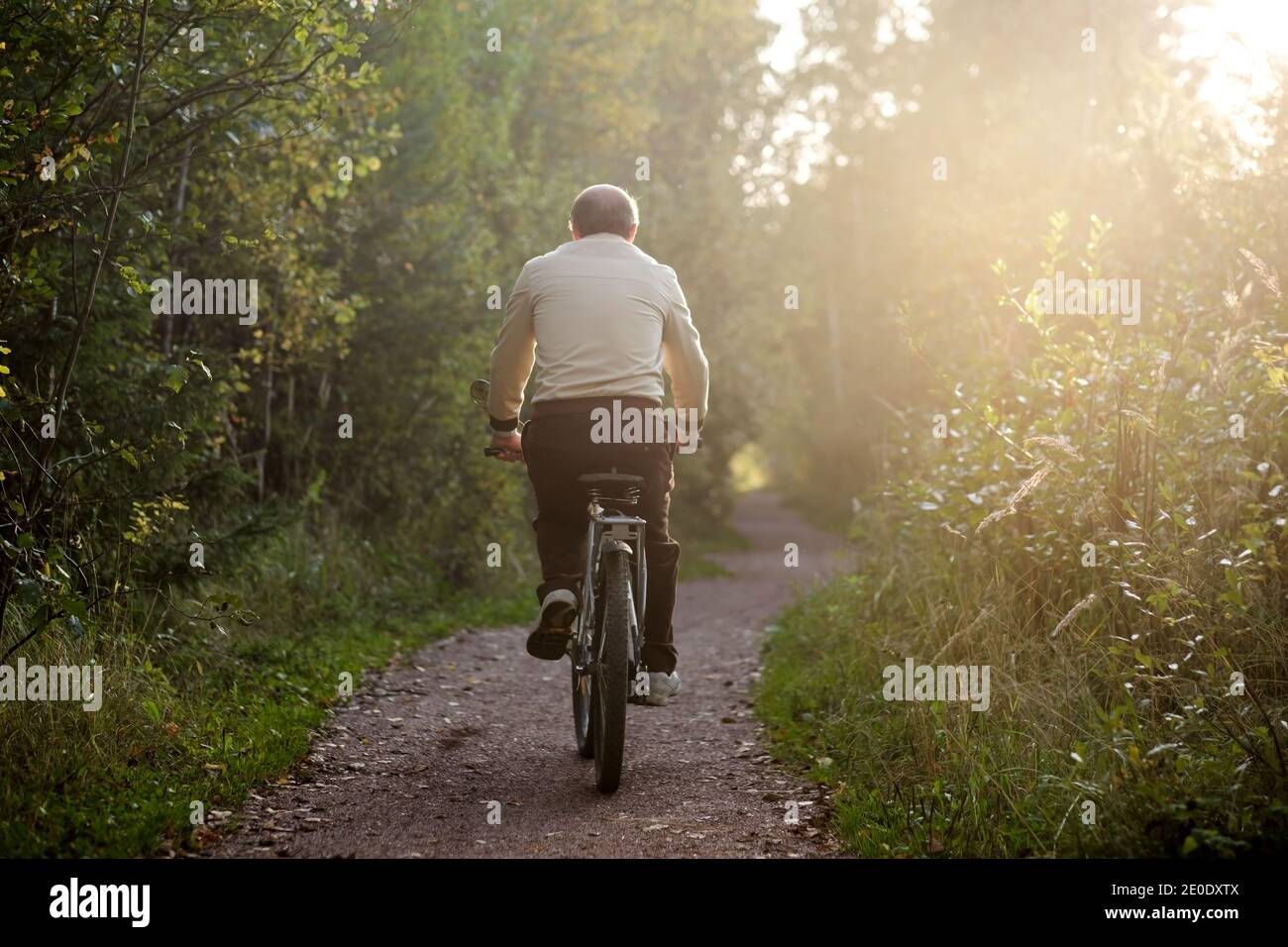 Vecchio uomo caucasico a cavallo di una bicicletta all'aperto sul sole giorno Foto Stock