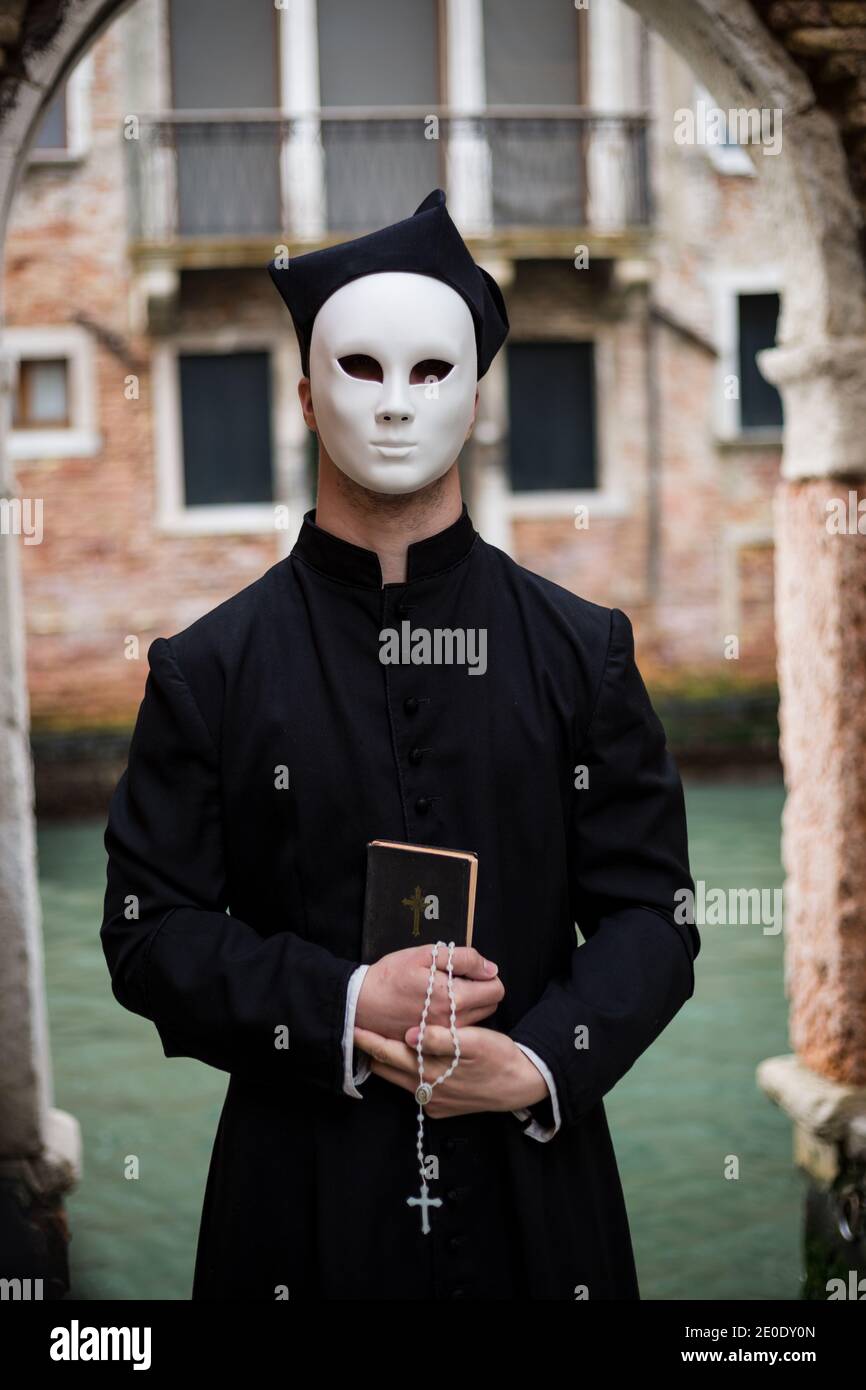 giovane sacerdote a venezia con maschera davanti al canale Foto Stock