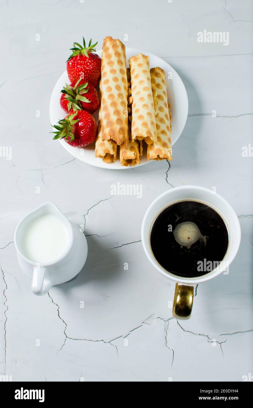 Sul tavolo si trova caffè caldo, crema e dolce dolce con fragole fresche Foto Stock