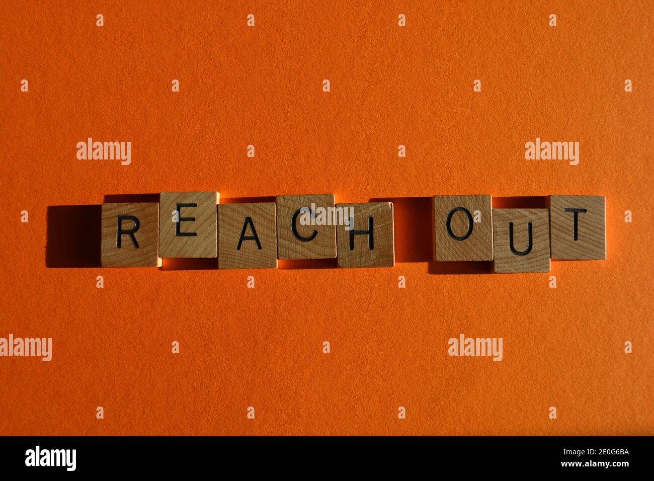 Raggiungi, parole in lettere alfabetiche in legno isolate su sfondo arancione Foto Stock