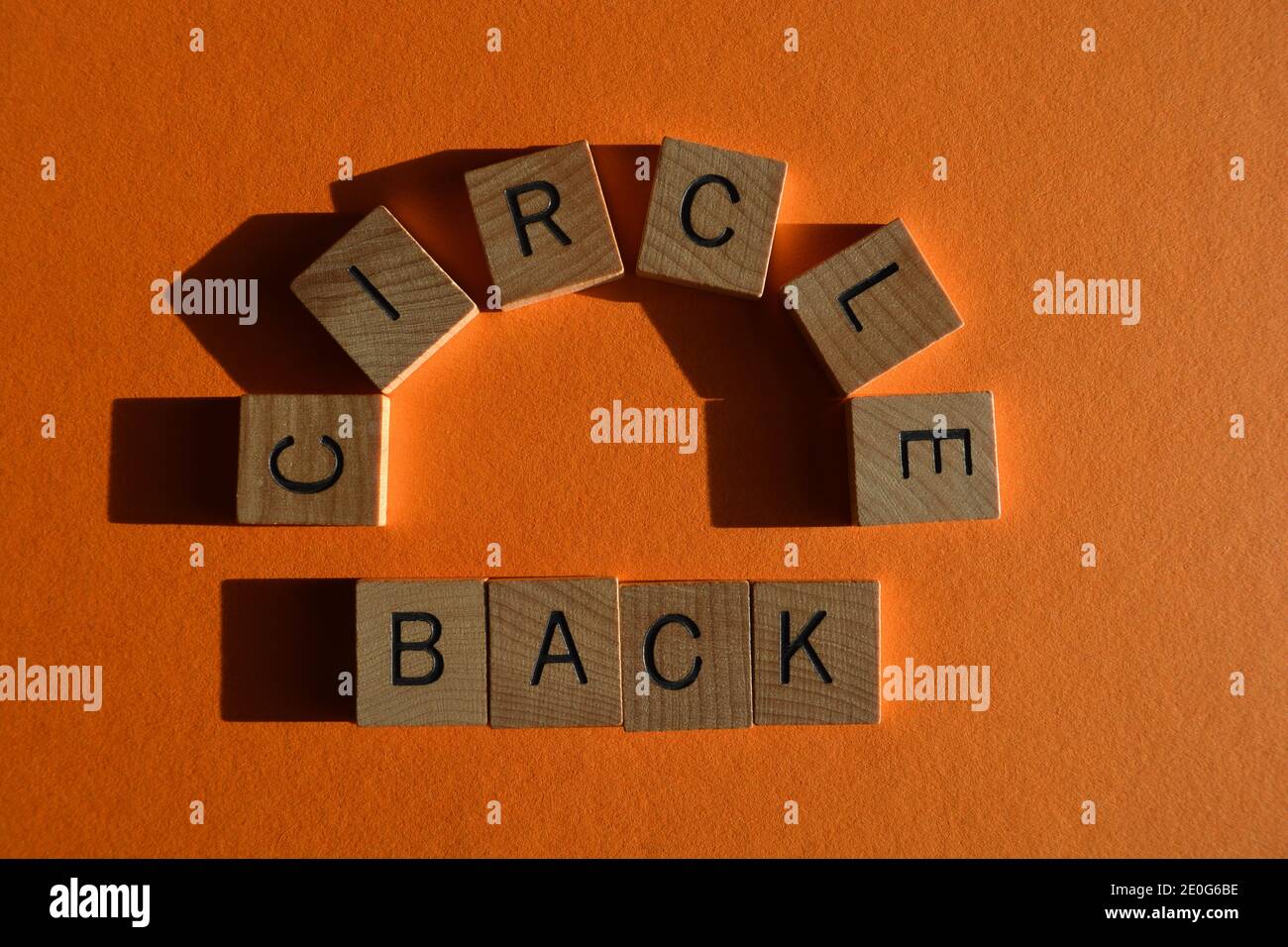 Circle Back, parole in lettere di legno isolate su sfondo arancione Foto Stock