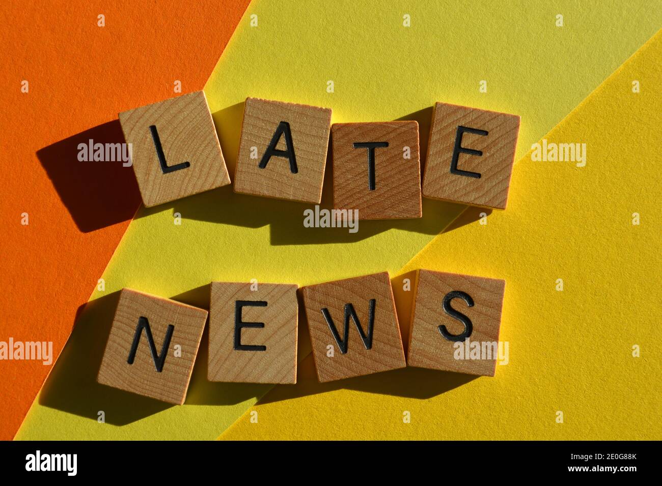 Ultime notizie, parole in lettere alfabetiche in legno isolate su sfondo giallo e arancione Foto Stock