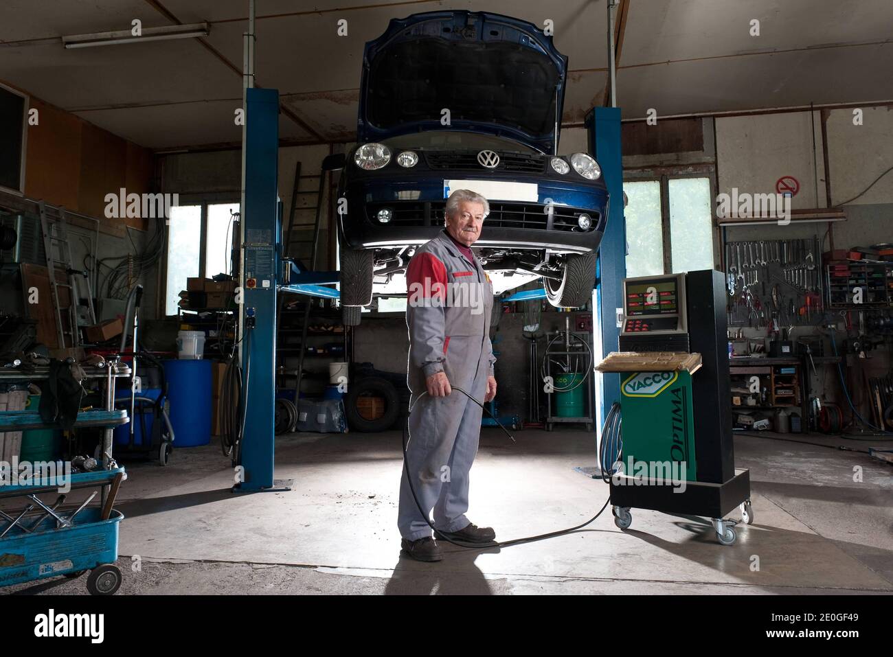Il meccanico di automobile Mathieu Camille, 69, posa al suo garage a Echenevex, Francia nell'aprile 2012. Il garage si trova a 111 m sopra il grande Hadron Collider (LHC) del CERN. LHC è un acceleratore di particelle utilizzato dai fisici per studiare le particelle più piccole conosciute, i blocchi fondamentali di tutte le cose. TEXTE: J'ai construit ce garage it 1978. Quelques annees Plus tard, une personne est passee et nous a expique que le CERN allait construire un anneau qui passera en-dessous. Nous avons alors ete expropries du sous-sol. Nous avons reçu une Petite compensation, c'etait pas une grosse somme. ma. Mais Foto Stock