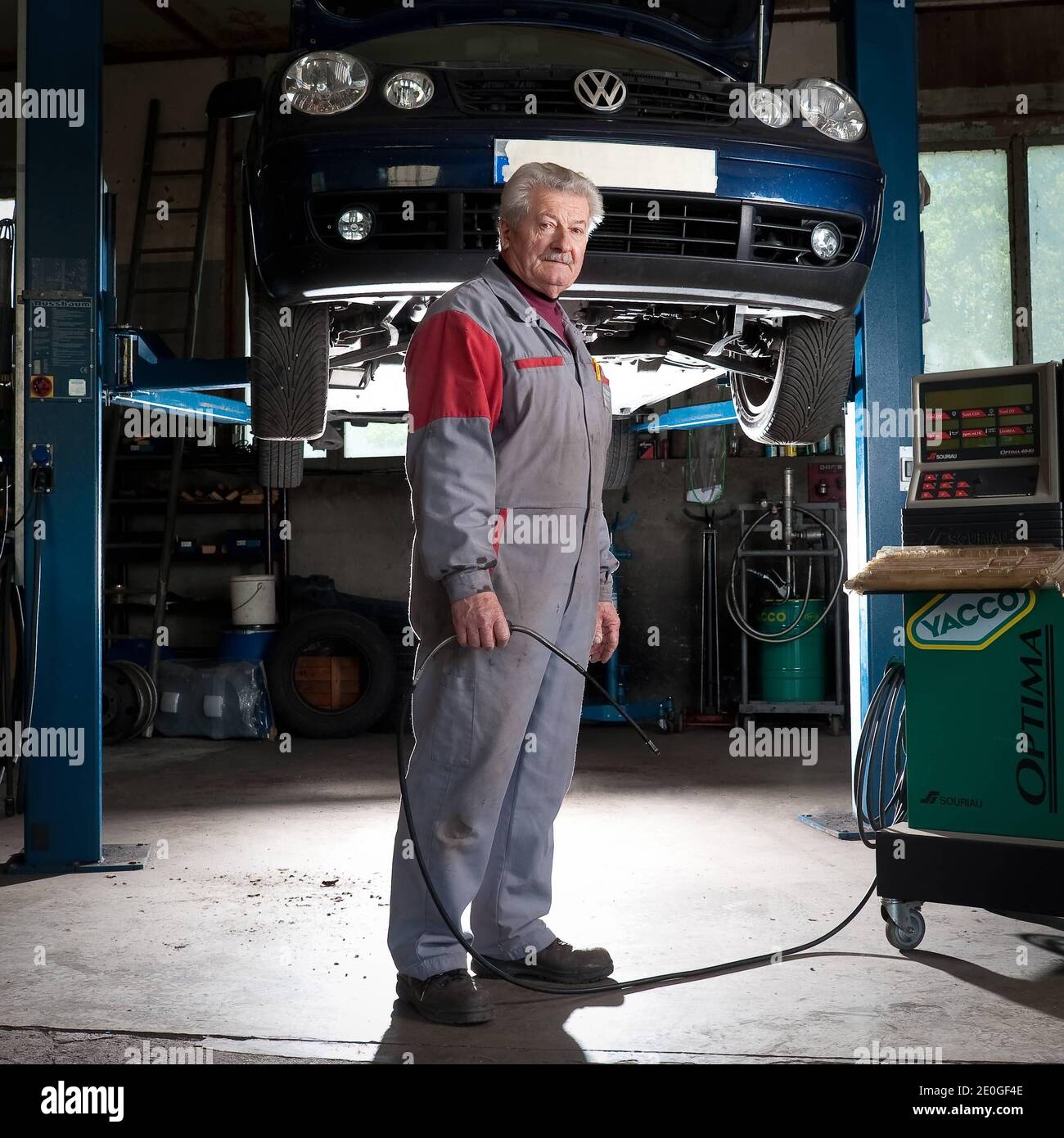 Il meccanico di automobile Mathieu Camille, 69, posa al suo garage a Echenevex, Francia nell'aprile 2012. Il garage si trova a 111 m sopra il grande Hadron Collider (LHC) del CERN. LHC è un acceleratore di particelle utilizzato dai fisici per studiare le particelle più piccole conosciute, i blocchi fondamentali di tutte le cose. TEXTE: J'ai construit ce garage it 1978. Quelques annees Plus tard, une personne est passee et nous a expique que le CERN allait construire un anneau qui passera en-dessous. Nous avons alors ete expropries du sous-sol. Nous avons reçu une Petite compensation, c'etait pas une grosse somme. ma. Mais Foto Stock