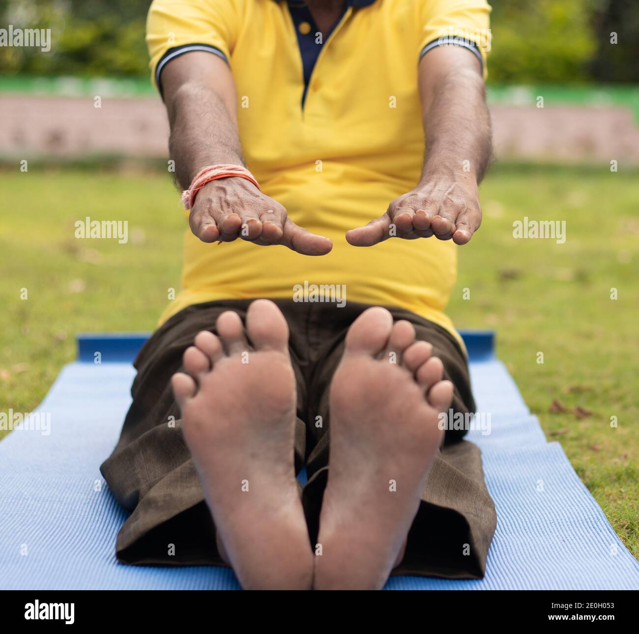 Vista ad angolo basso di un vecchio non riconoscibile seduto in giù sull'esercitazione o sul tappeto di yoga che tocca i suoi piedi - concetto di salute e di idoneità attive felici anziani. Foto Stock