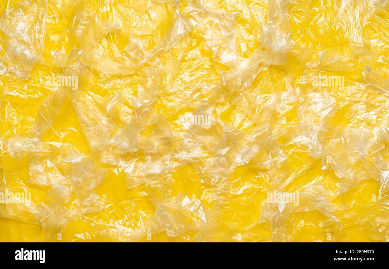 Vista dall'alto con una moltitudine di sacchetti monouso su sfondo giallo. Fondo full-frame con molti sacchetti di plastica. Foto Stock