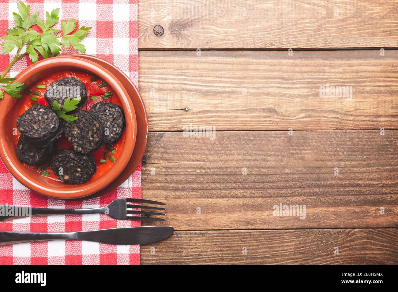 Pudding nero in pentola di argilla su base rustica di legno e tovaglia a scacchi. Tapas spagnole. Foto Stock