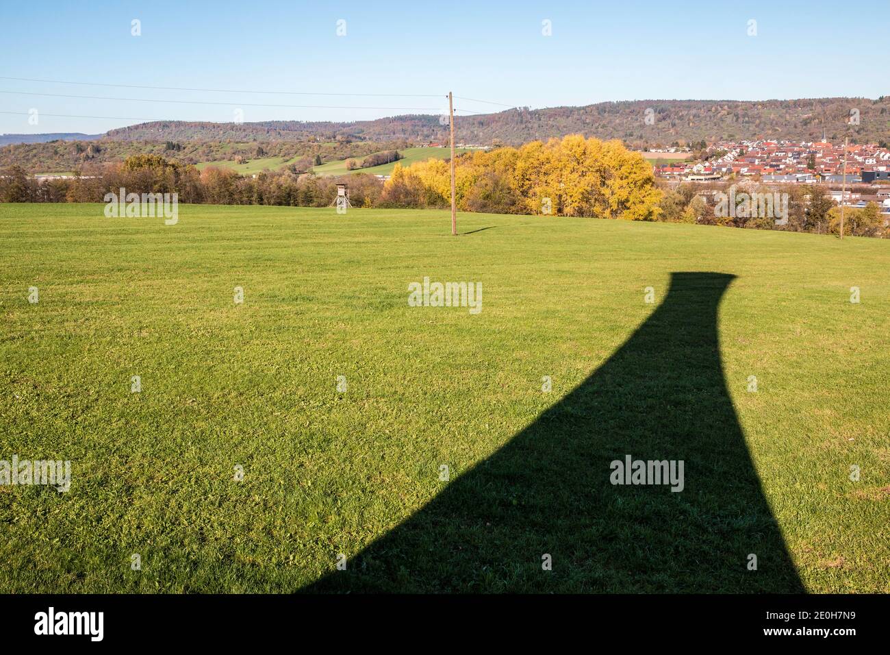 Ombra nera di una torre sul campo verde vicino la città Foto Stock