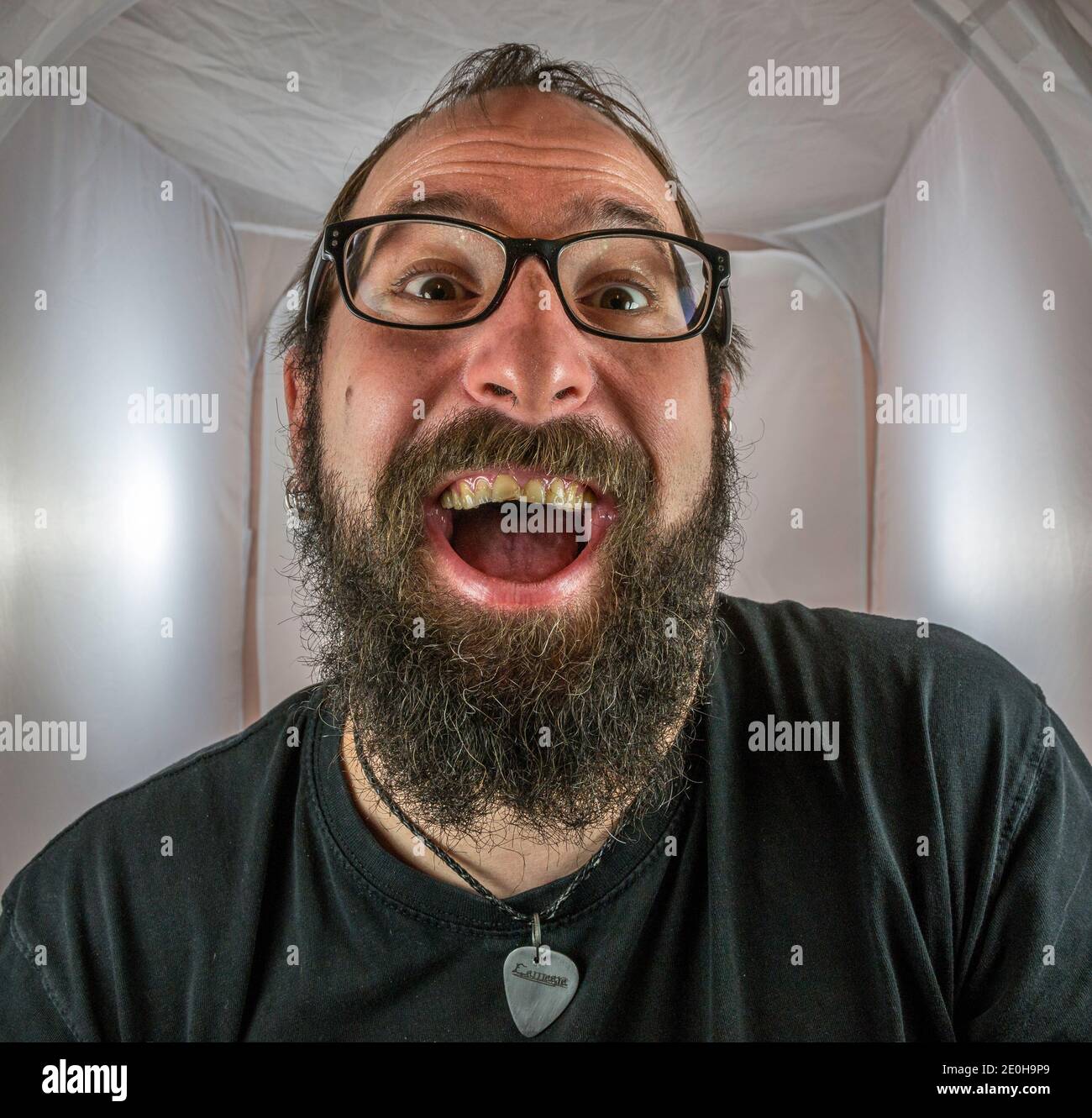 Un uomo bearded gleeful e gloating in un buon umore con occhiali neri Foto Stock