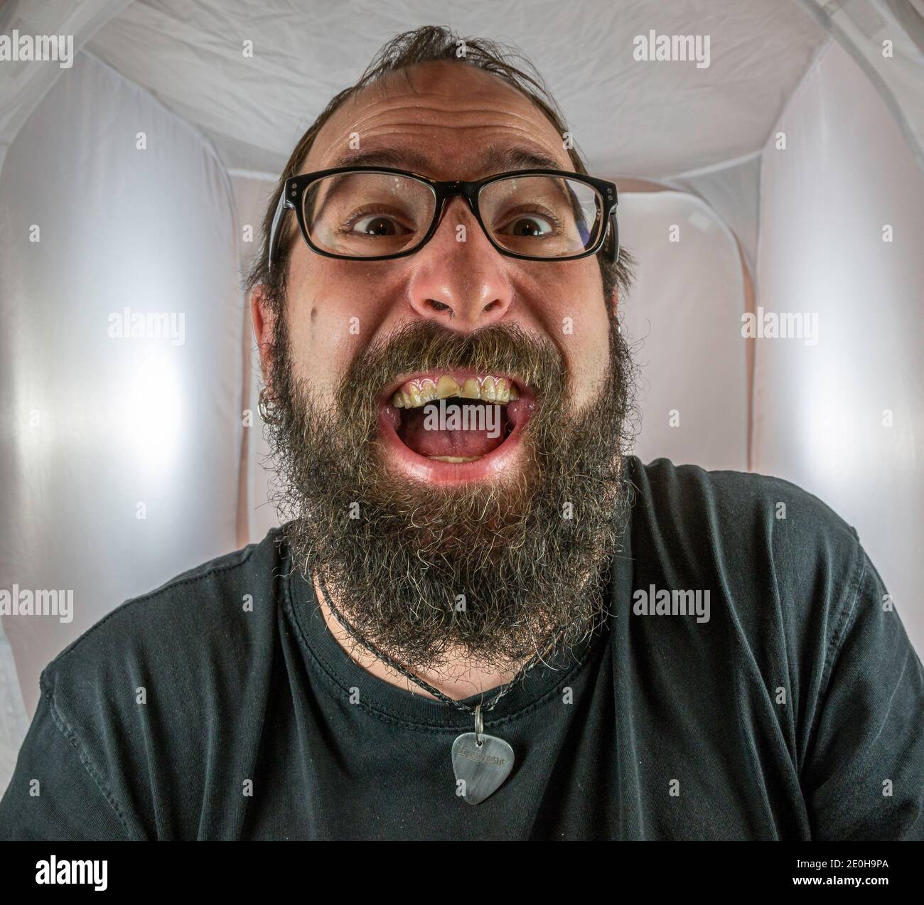 Un uomo bearded gleeful e gloating in un buon umore con occhiali neri Foto Stock