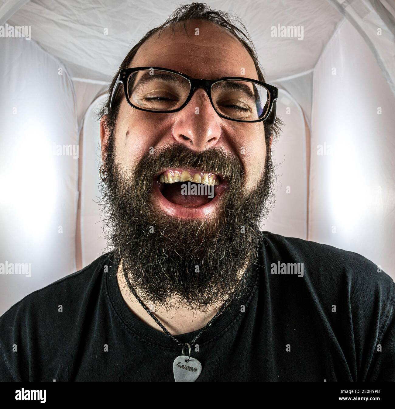 Un uomo bearded gleeful e gloating in un buon umore con occhiali neri Foto Stock