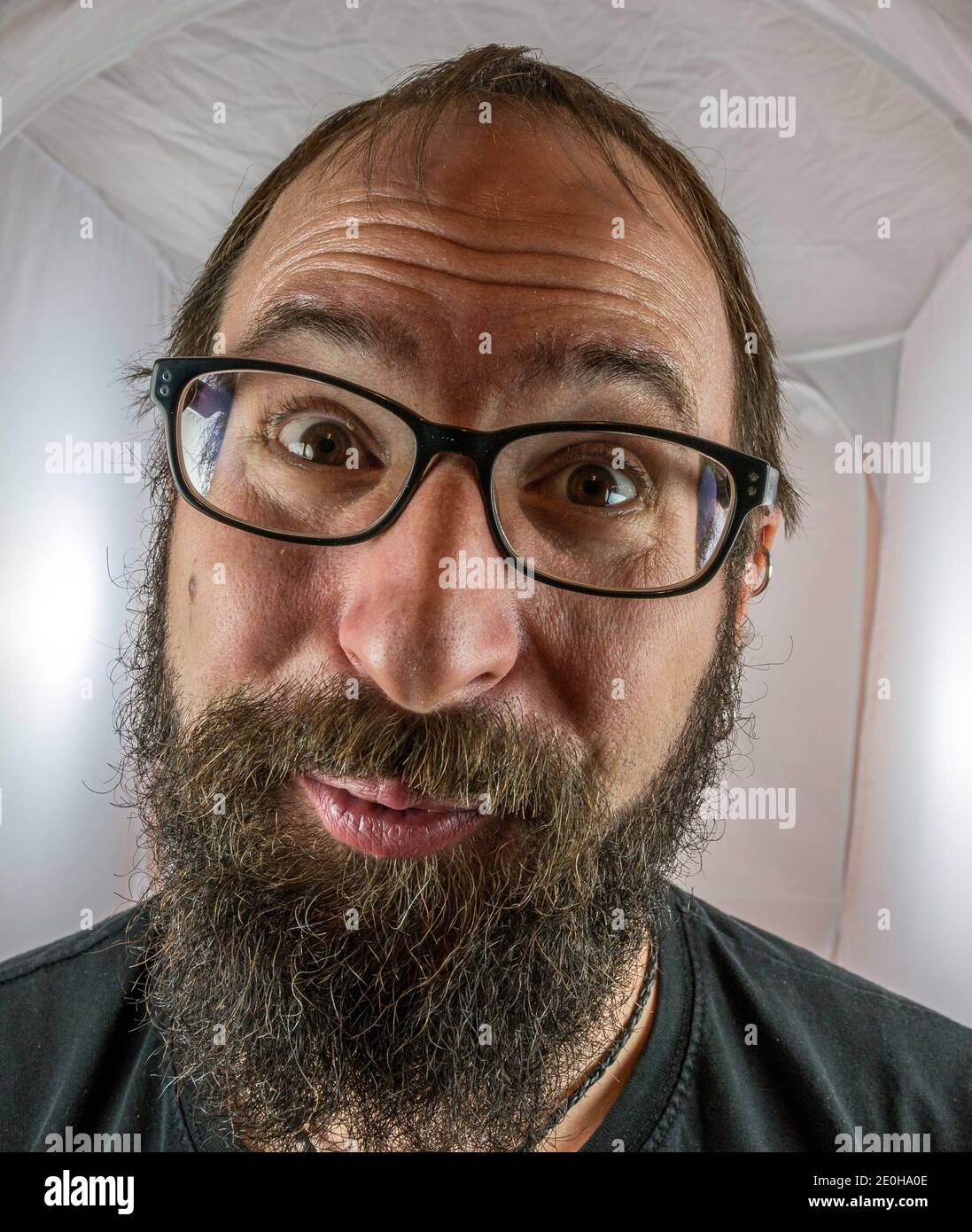 Un uomo bearded sorridente di buon umore con nero occhiali Foto Stock