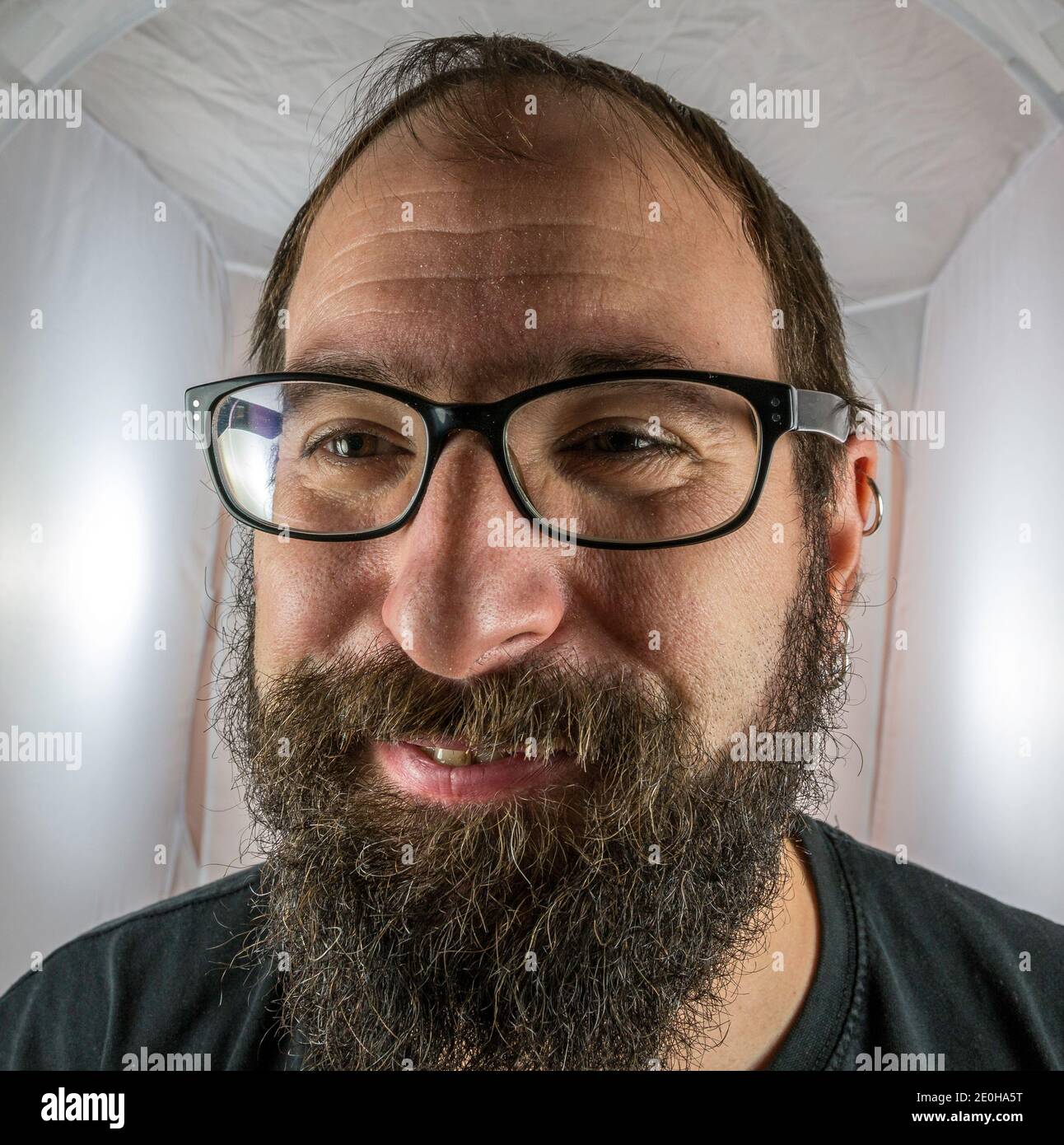 Un uomo bearded sorridente di buon umore con nero occhiali Foto Stock