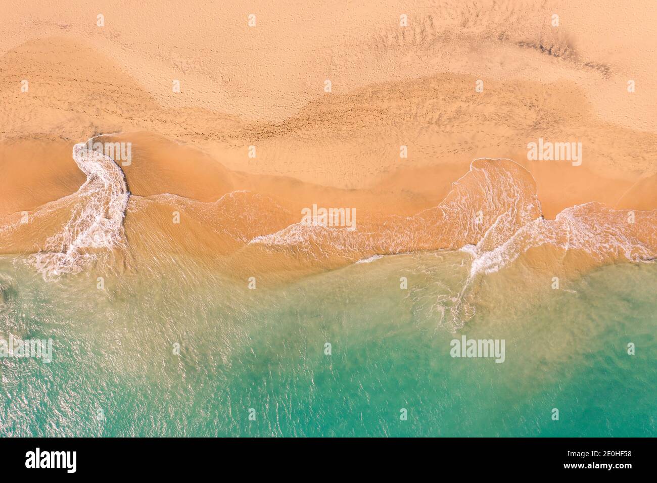 Vista aerea dall'alto verso il basso della splendida costa dell'oceano Atlantico con acque cristalline turchesi e spiaggia sabbiosa, onde che si avvolgono nella riva Foto Stock