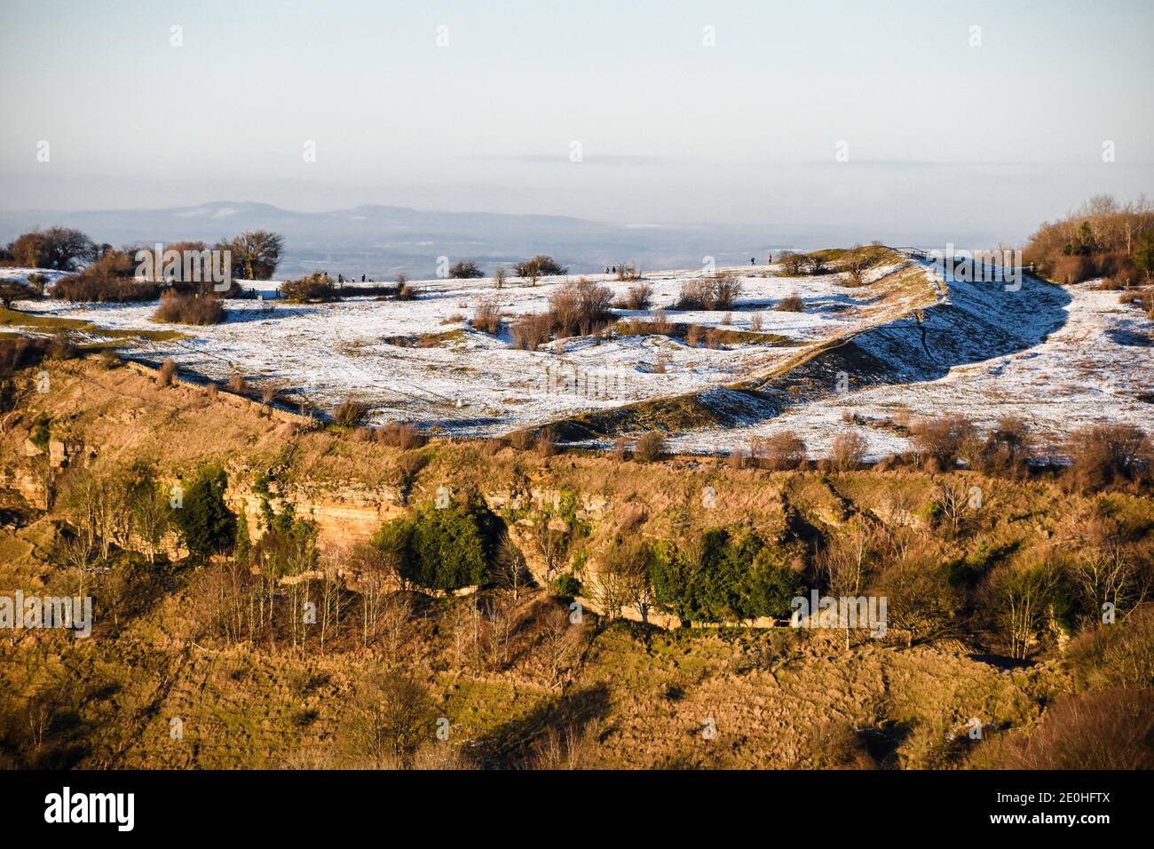 Crickley Hill - scarpata di Cotswold e antiche fortificazioni - illuminato al sole in inverno con una leggera copertura di neve. REGNO UNITO Foto Stock