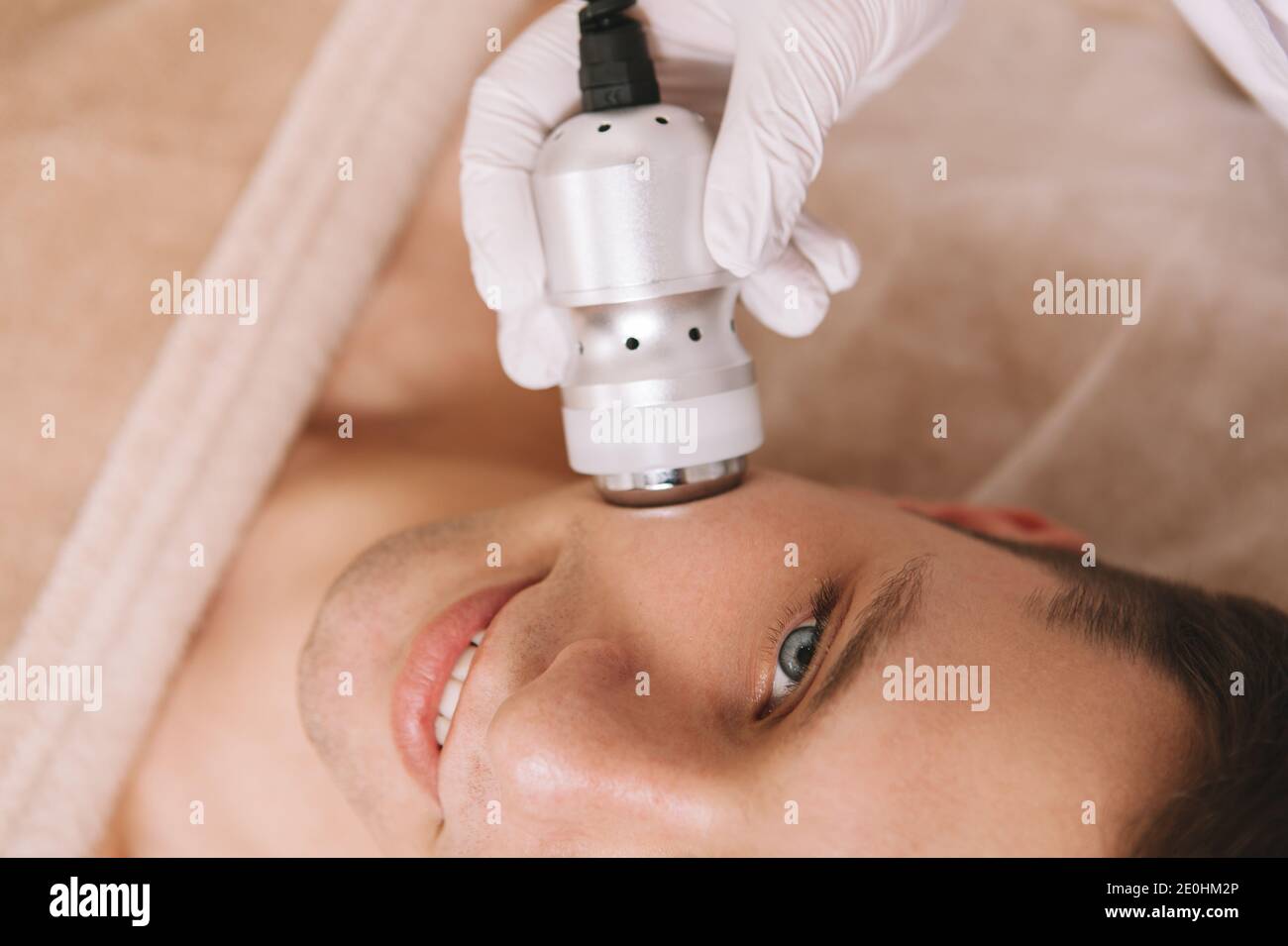 Vista dall'alto ritagliata di un bell'uomo che gode di hardware trattamento  della pelle da parte di un cosmetologo Foto stock - Alamy