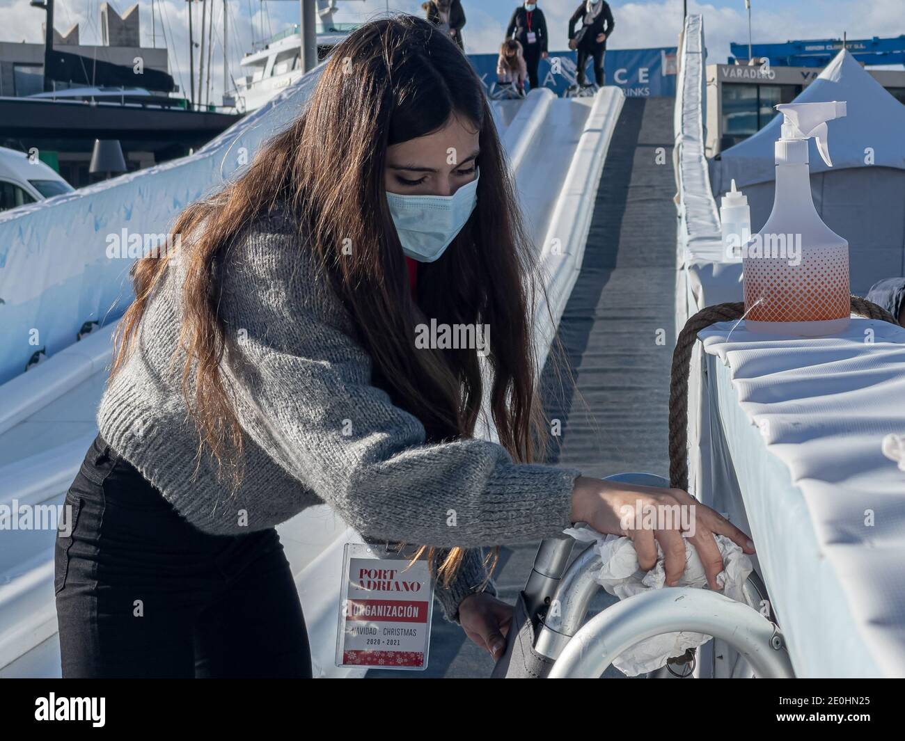 Giovane donna che indossa una maschera medica durante la disinfezione delle slitte su un vetrino durante la pandemia di Covid-19 a Port Adriano, Maiorca. Foto Stock