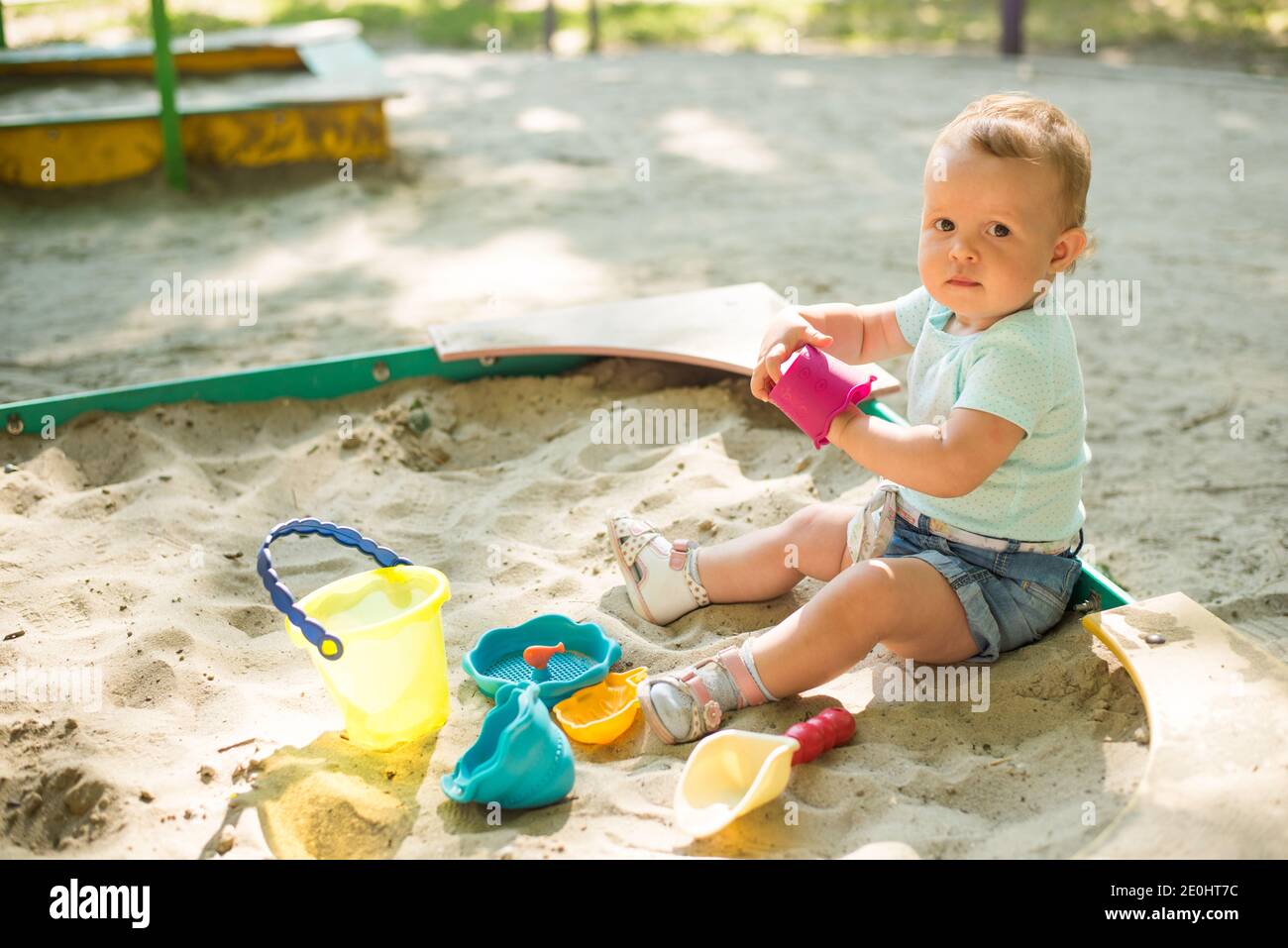 Adorabile gioco del bambino con sabbia in sandbox sul parco giochi Foto Stock