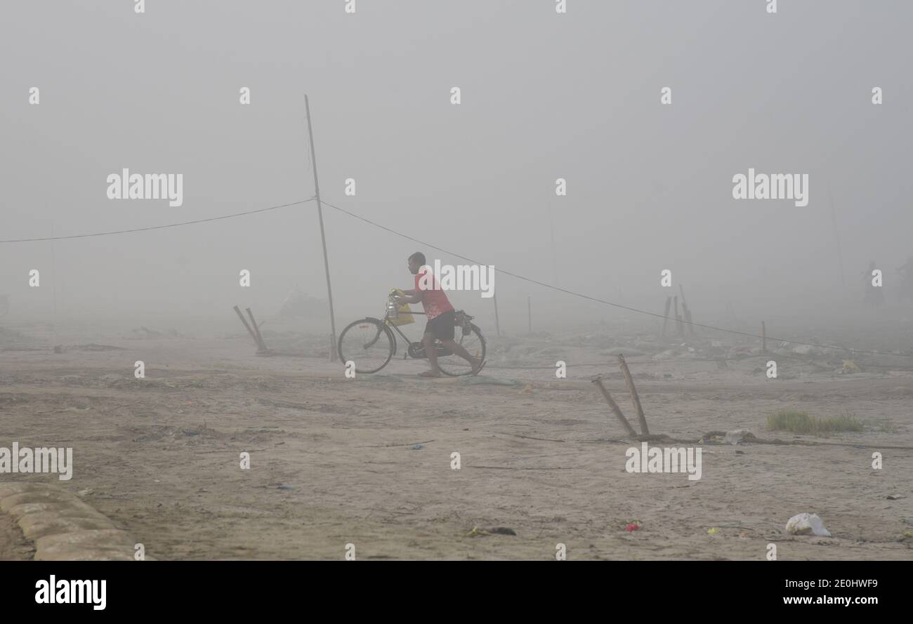 Guwahati, Assam, India. 31 dicembre 2020. Un uomo spingeva la sua bicicletta sulla riva del fiume Brahmaputra in una mattinata di nebbia a Guwahati Assam India venerdì 1 gennaio 2021. Il fiume Brahmaputra è uno dei fiumi più grandi dell'Asia, che scorre dalla regione cinese del Tibet ed entra in India Credit: Dasarath Deka/ZUMA Wire/Alamy Live News Foto Stock