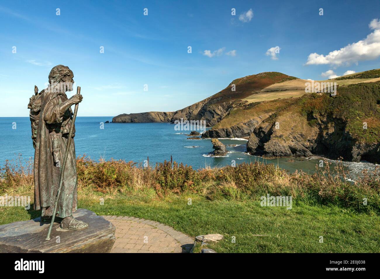 La statua di San Carannog custodisce la baia di Llangrannog, con il dente di Bica e il promontorio di Ynys Lochtyn sullo sfondo. Foto Stock