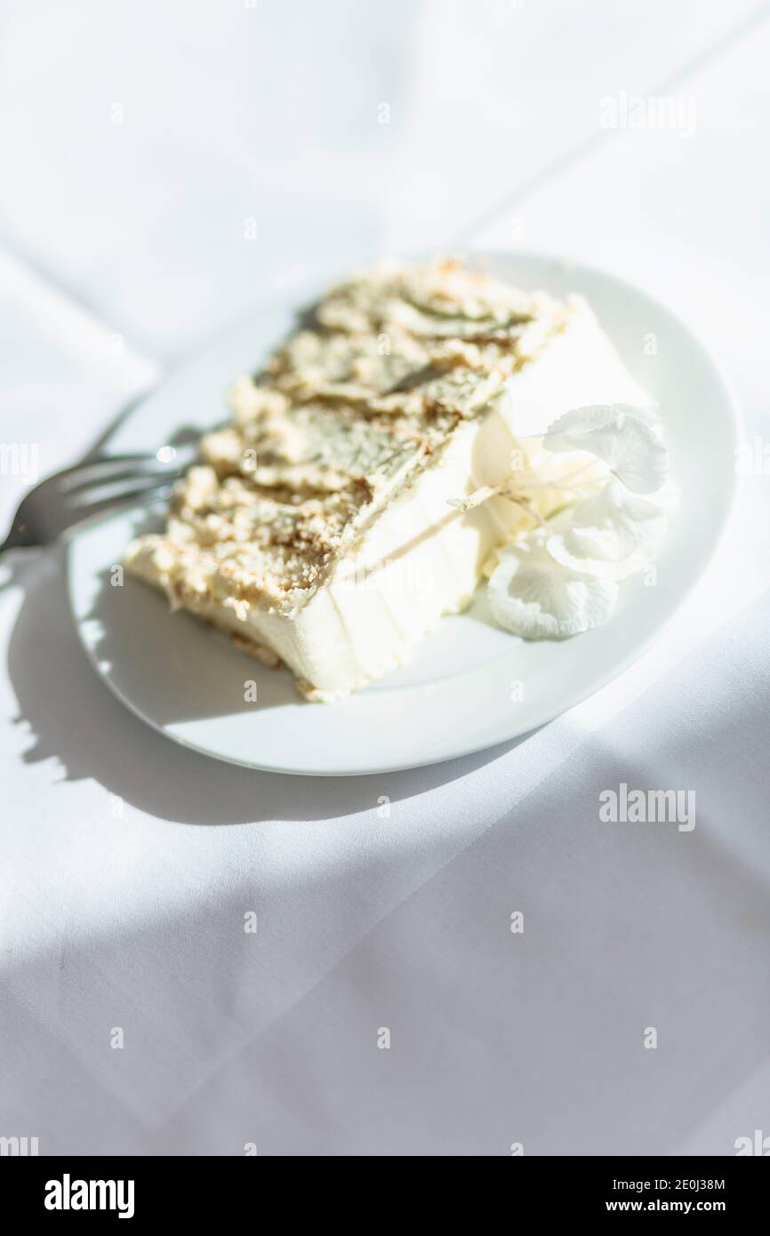 Fetta di torta nuziale (torta di fiori di sambuco) su tovaglia bianca Foto Stock