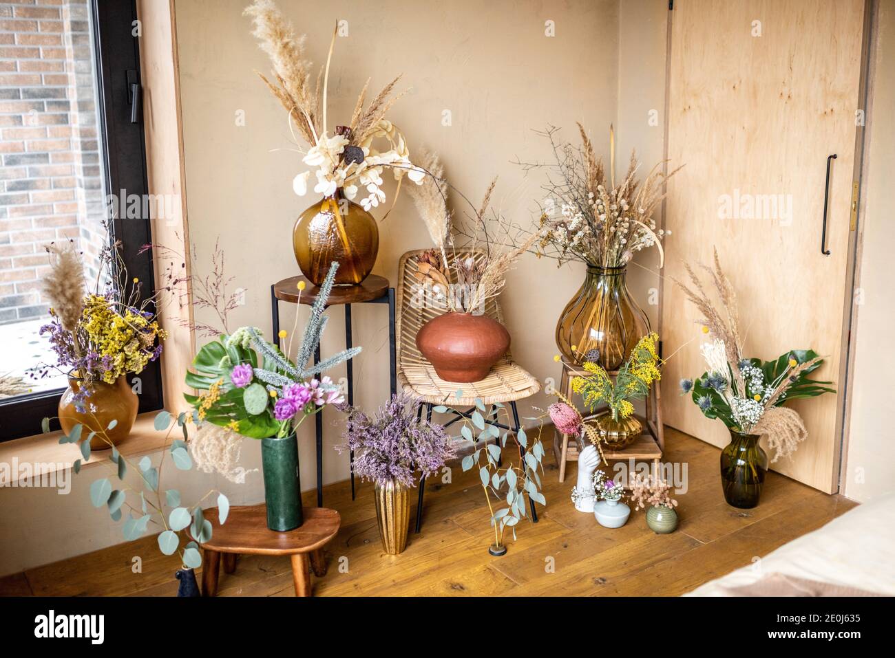 Varietà di diverse composizioni di fiori secchi e freschi e. erbe in una stanza con pareti beige Foto Stock