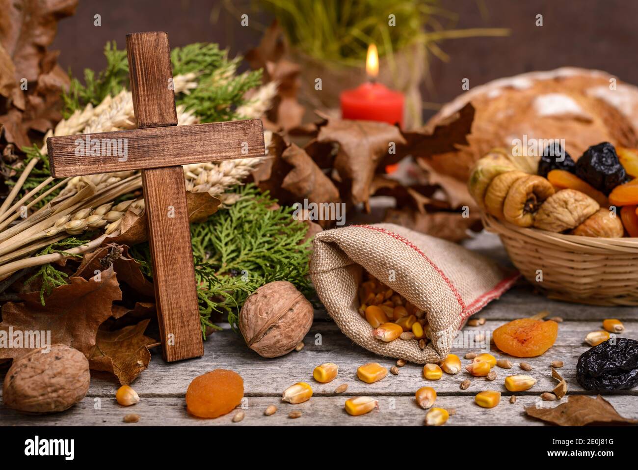 Cibo tradizionale per la vigilia di Natale ortodossa. Yule log o badnjak, croce di legno, pane, cereali frutta secca e candela bruciante su tavola rustica. Concep Foto Stock