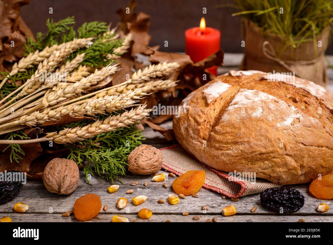 Cibo tradizionale per la vigilia di Natale ortodossa. Yule log o badnjak, pane, cereali, frutta secca e candela bruciante su tavolo di legno. Celebrazione concettuale Foto Stock