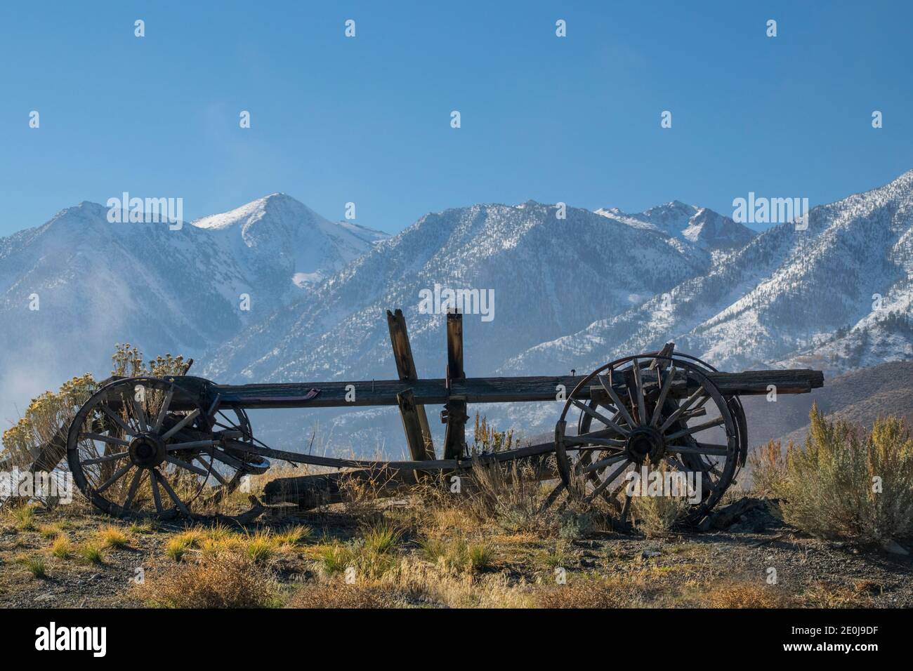 Un vecchio carro trainato da bue torna lentamente alla polvere sullo sfondo delle alte montagne della Sierra Nevada. Perché il carro è stato abbandonato? Foto Stock