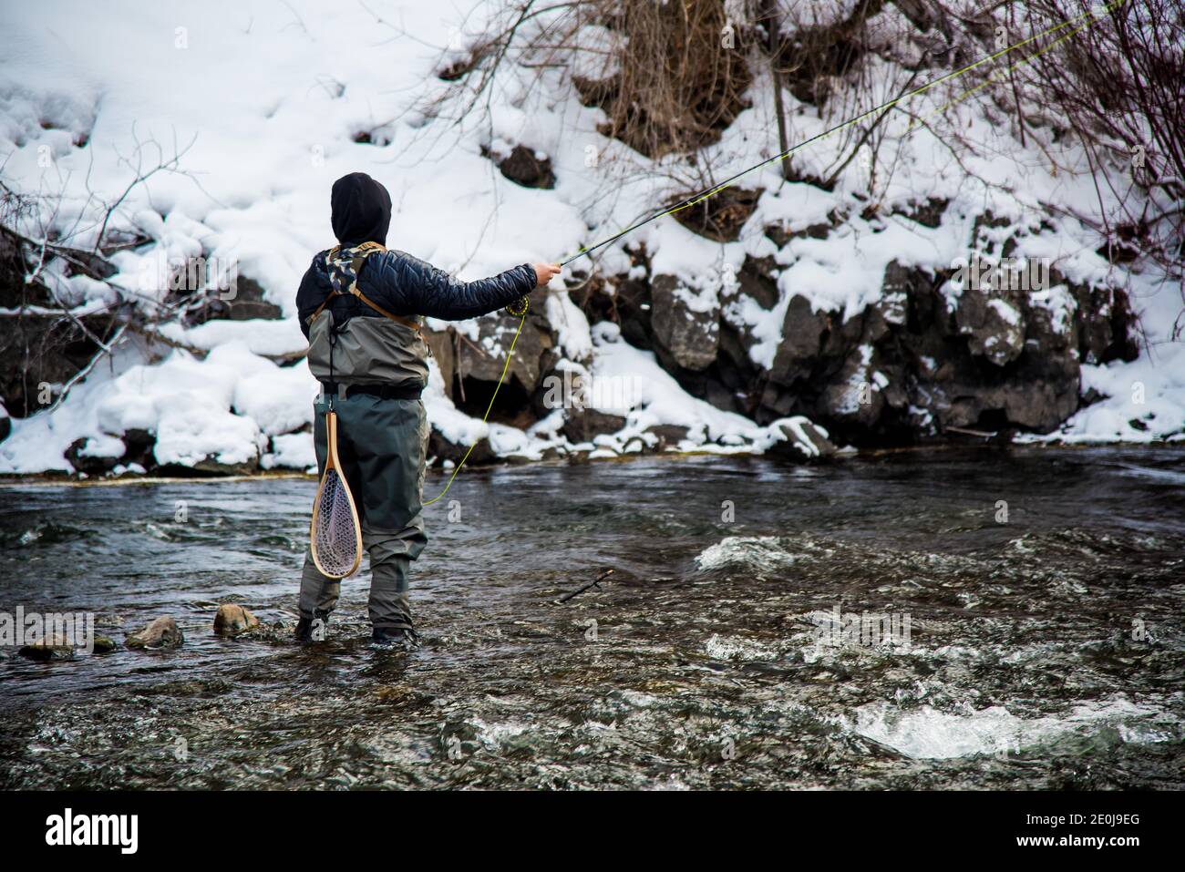 Fly pescatore, la pesca nelle acque fredde dell'inverno. Passione e interesse per lo sport sono necessari in queste temperature frigide. Foto Stock