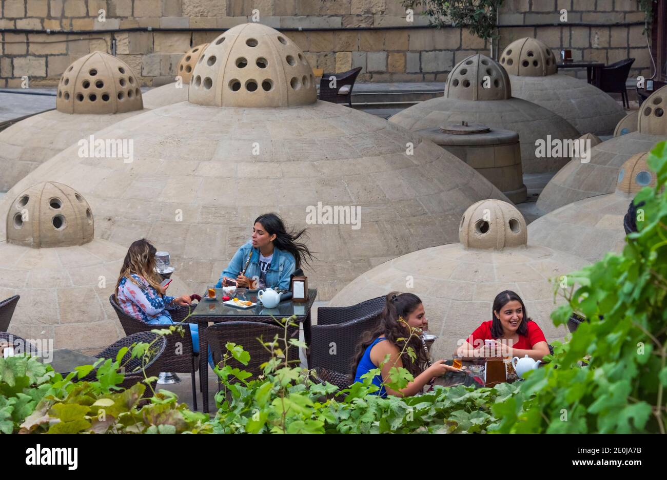 I giovani si rilassano e fumano Hookah sul tetto della Bathhouse di Haji Gayib nella Città Vecchia, Baku, Azerbaigian Foto Stock
