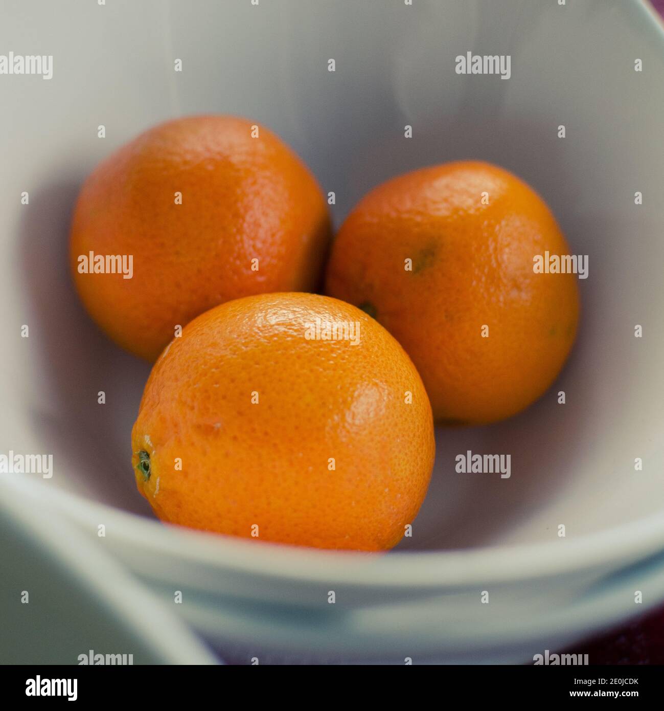 tre arance fresche in un recipiente bianco Foto Stock