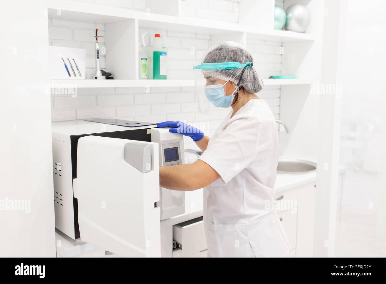 Sterilizzazione di strumenti medicali in autoclave. Operatore medico che indossa una maschera facciale protettiva. Strumenti medici sterili Foto Stock