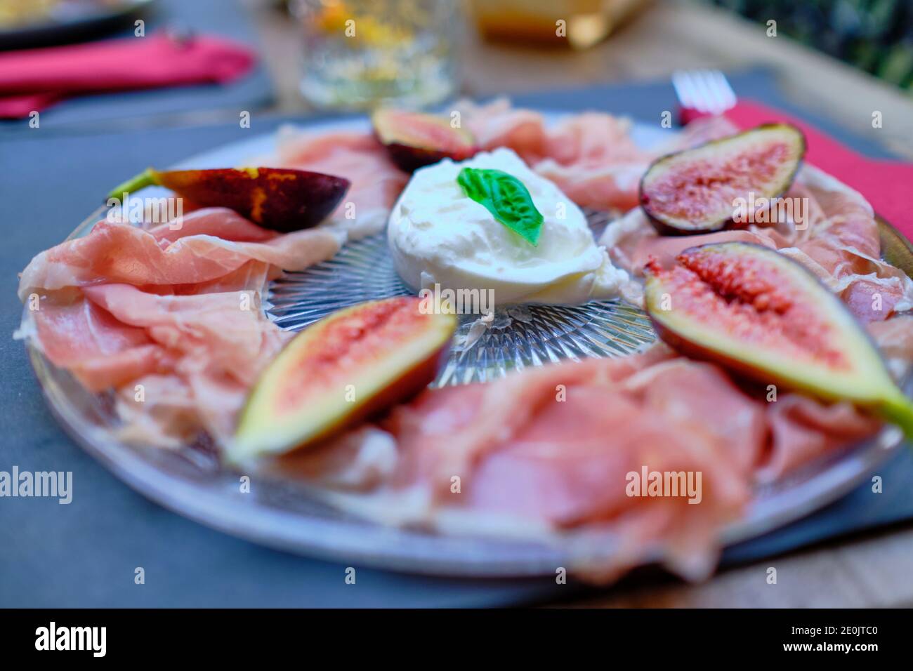 Un piatto tipicamente italiano freddo: Burrata, fichi e prosciutto crudo. Viene servito come antipasto in estate, quando i fichi sono frutta di stagione. Foto Stock