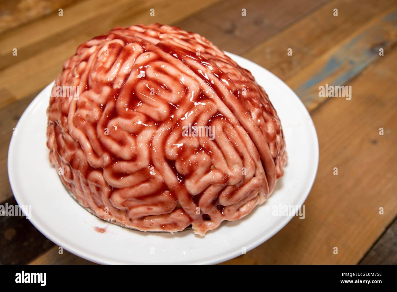 Una torta a forma di cervello con fragola fonte spazzolato su di esso per fare il pan di spugna guardare come un cervello sanguinoso umano reale per la parte di halloween Foto Stock