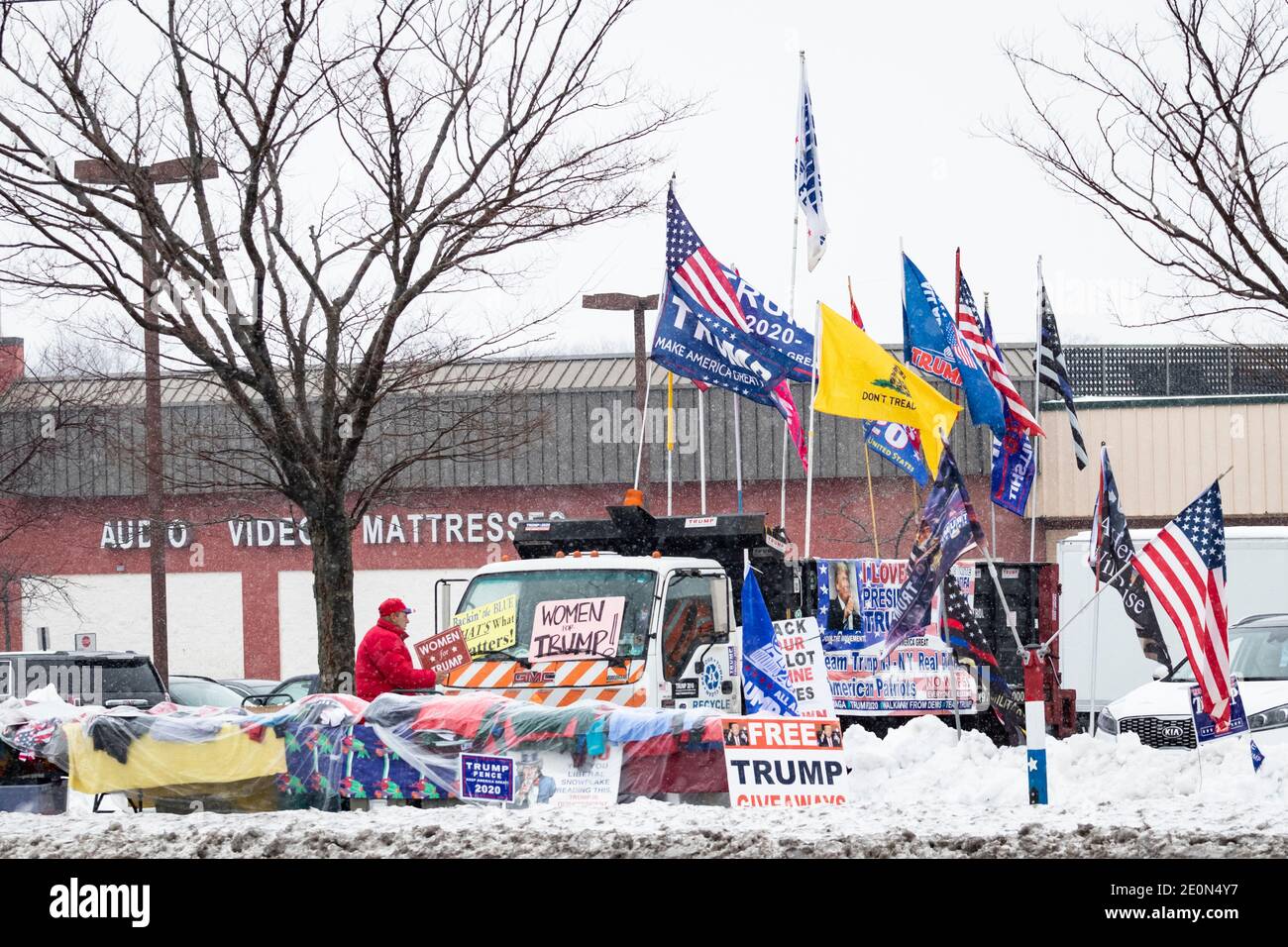 Molto tempo dopo che Donald Trump ha perso le elezioni del 2020, un uomo decora il suo camion con un cartello 'Donne per Trump' e altre bandiere e bandiere pro-Trump Foto Stock