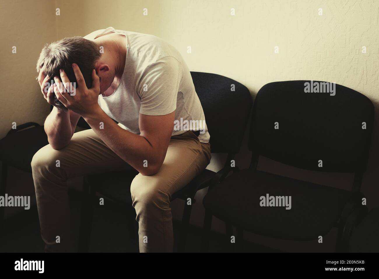 I problemi degli uomini. Un giovane si siede su una sedia e tiene la testa nelle mani. Foto Stock