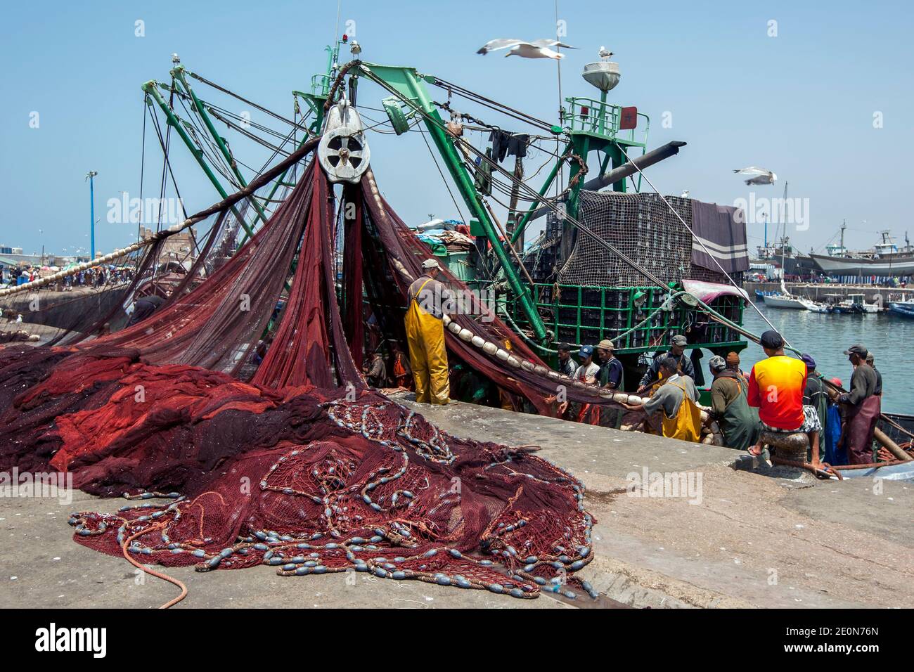 I pescatori ritornano in un peschereccio da traino con le loro catture al porto trafficato di Essaouira, sulla costa dell'Oceano Atlantico del Marocco. Foto Stock