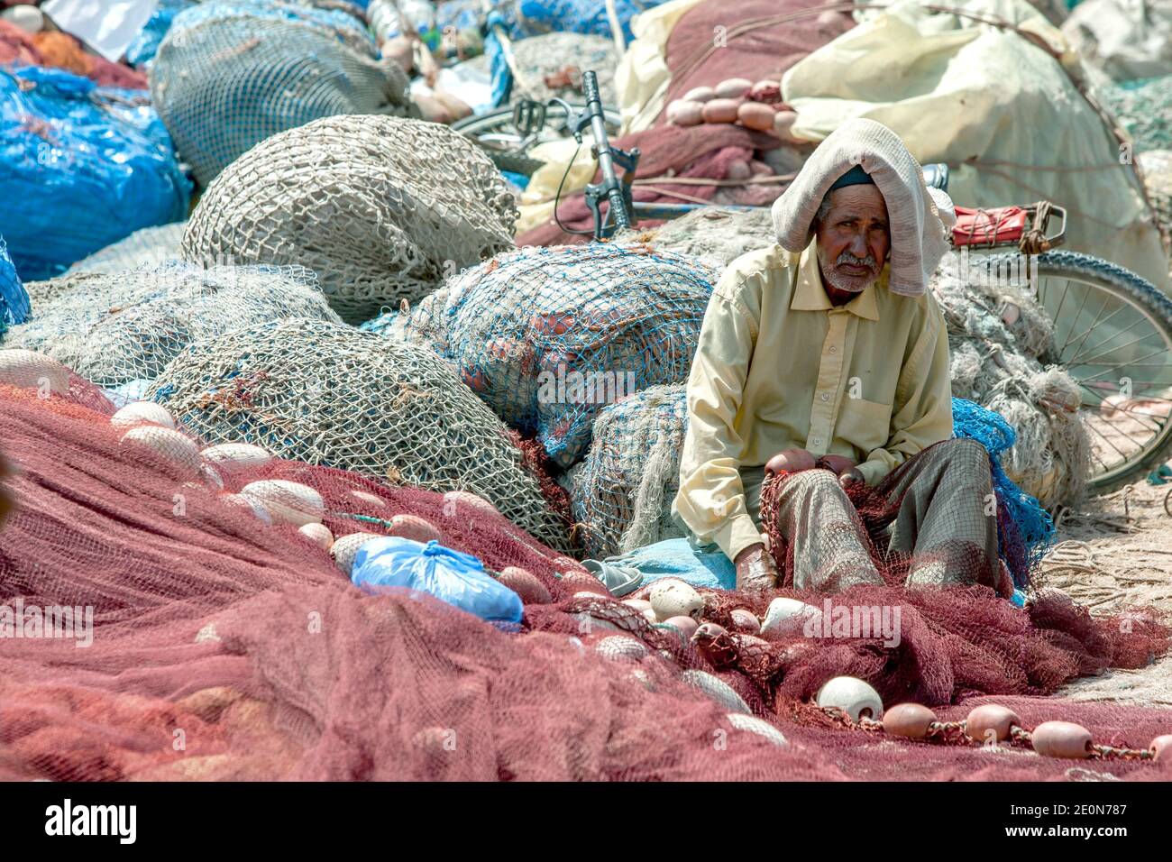 Un anziano che effettua riparazioni di una rete di pesca nel porto di Essaouira sulla costa dell'Oceano Atlantico del Marocco. Foto Stock