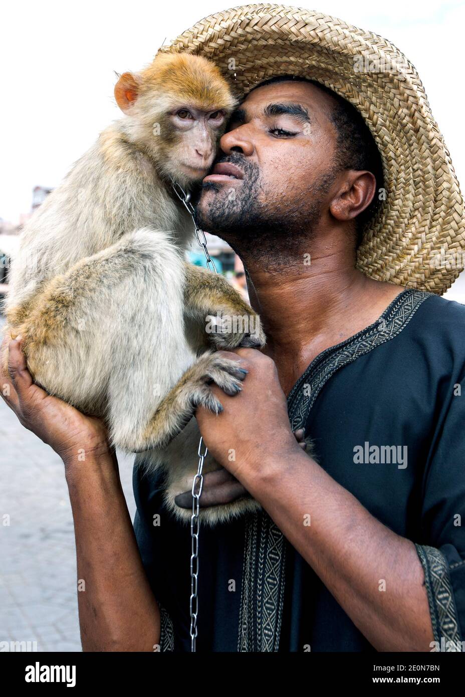 Un uomo posa per una fotografia con la sua scimmia a Djemaa el-Fna, la piazza principale della medina di Marrakech in Marocco. Foto Stock