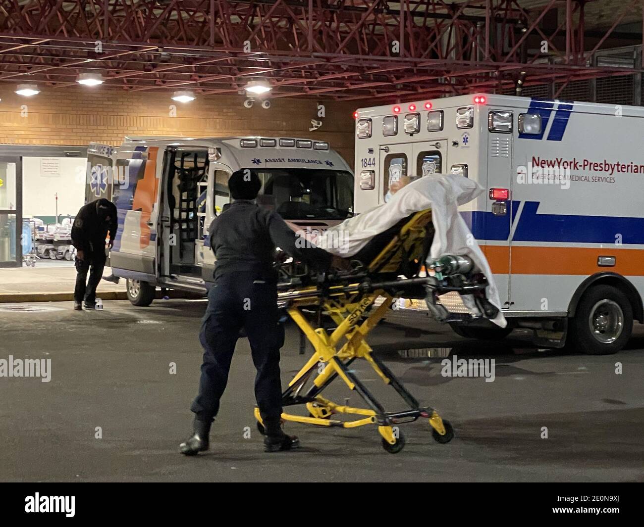 New York, New York, Stati Uniti. 31 dicembre 2020. I pronto soccorso di New York non conoscevano la tregua di Capodanno. Gli ospedali hanno continuato ad ammettere i pazienti l'ultima sera dell'anno. Questa paramedica femminile è appena arrivata con un nuovo paziente, una donna mascherata di viso anziana, sta andando a dirigersi al pronto soccorso dell'ospedale Bellevue a Manhattan che è stato in pieno svolgimento durante la pandemia. I ricoveri di Covid hanno superato 7,800 e sono al loro più alto livello dal 7 maggio. Non meno di 166 persone sono morte l'ultimo giorno dell'anno. I decessi, che sono i più lenti a salire, sono saliti del 36 per cento Foto Stock