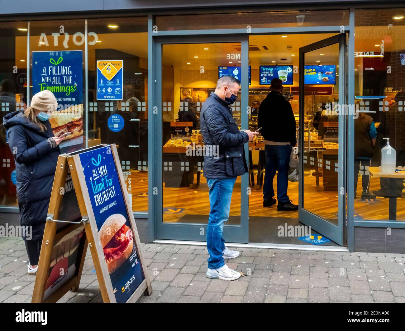 Clienti social distancing mentre si accodano alla caffetteria Greggs on Il giorno di Santo Stefano in attesa di acquistare bevande e cibo da portare via Foto Stock