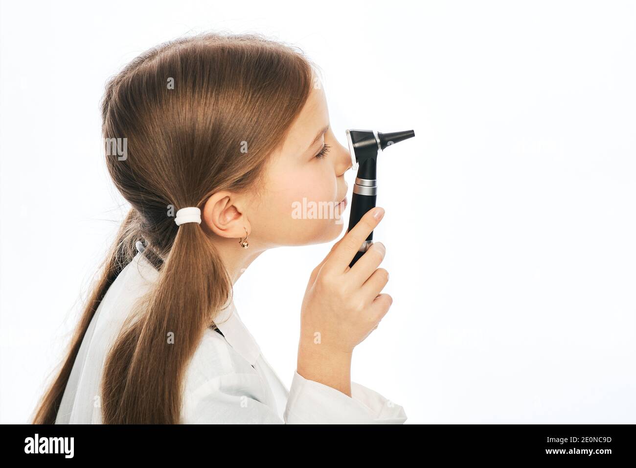 Bella bambina che gioca medico oftalmologo con un oftalmoscopio. Vista laterale, sfondo bianco Foto Stock