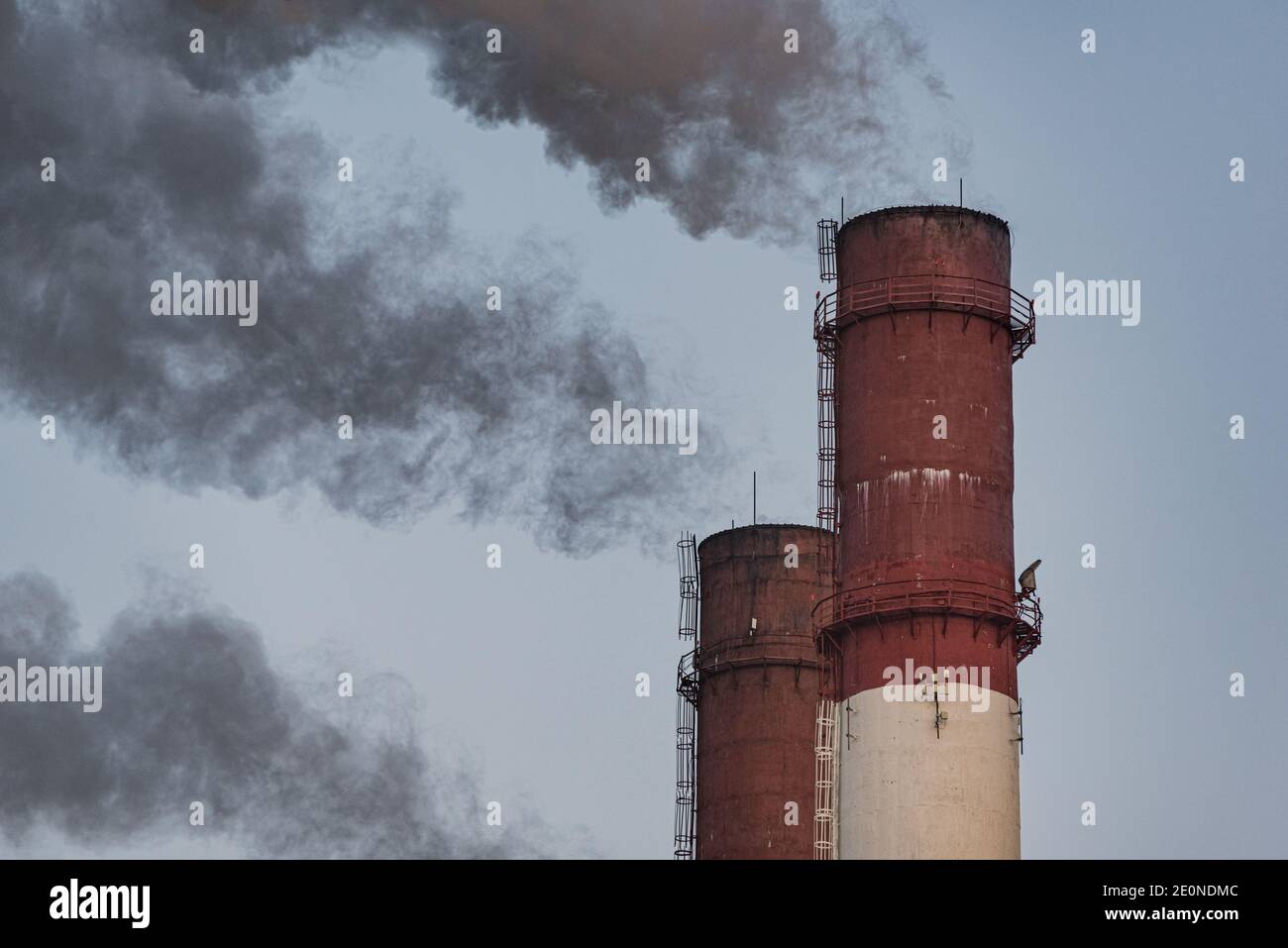 I tubi della centrale termica eruttano fumo scuro nell'aria. Concetto di inquinamento e riscaldamento globale. San Pietroburgo, Russia. Foto Stock