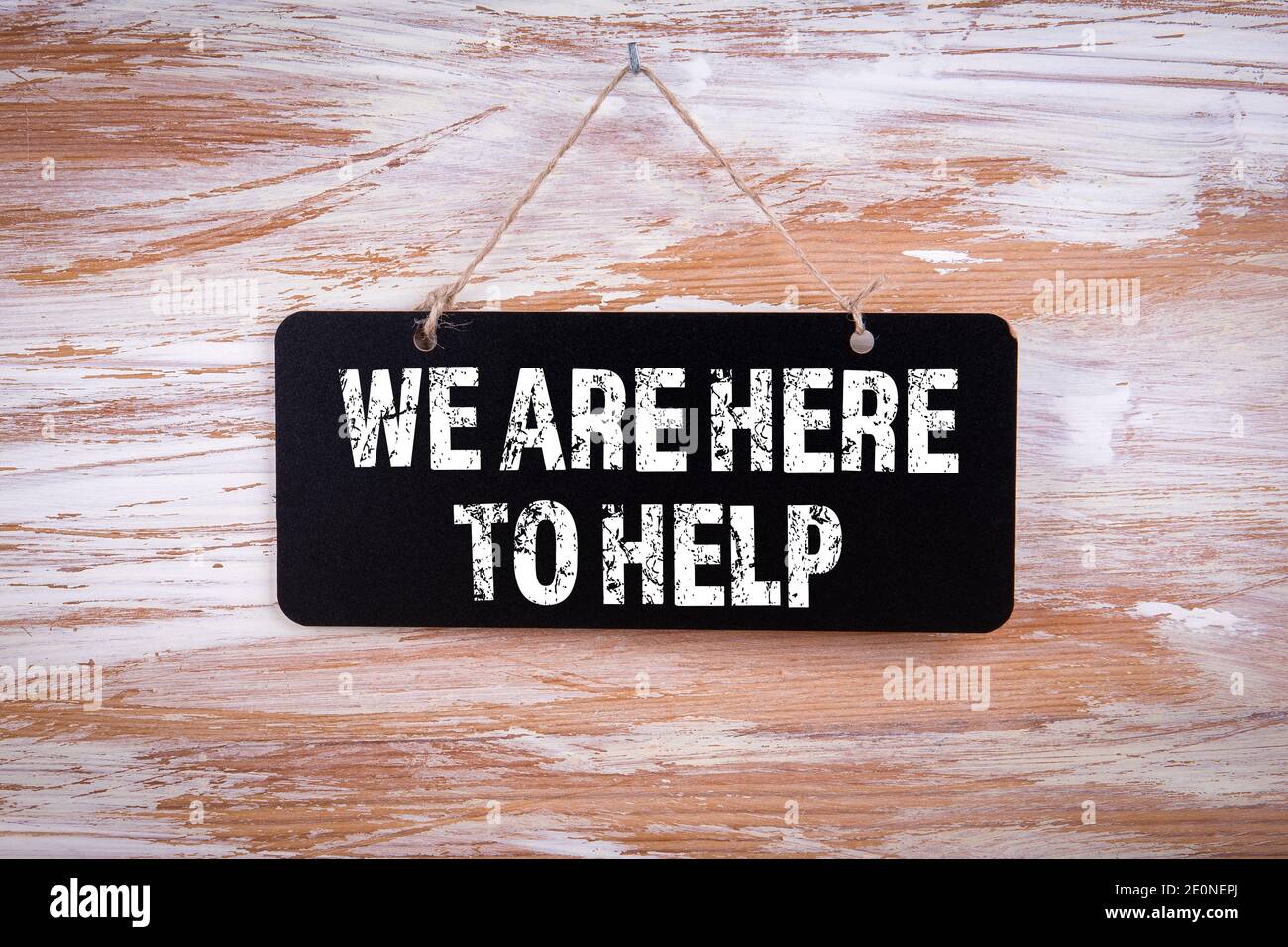 Siamo qui per aiutarvi. Tavolo di gesso appeso su un muro di legno. Foto Stock